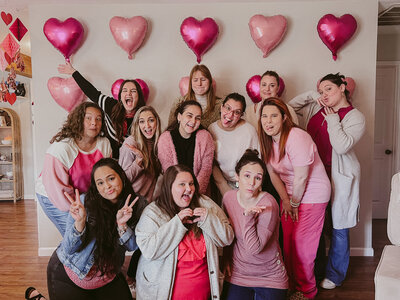 A group of women doing silly poses in front of a heart balloon wall at a Galentine's Day Party in Alvin Texas