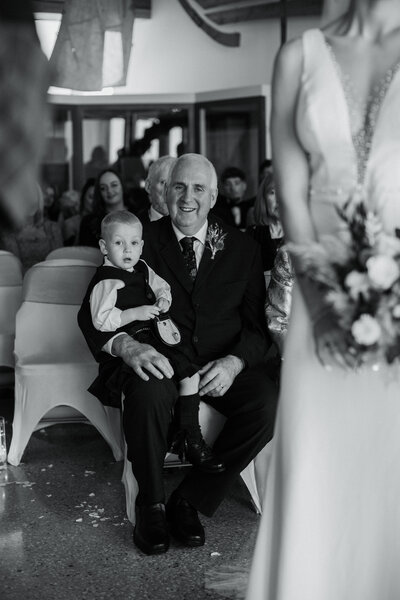 Father of the bride holding his grandson during cereomony