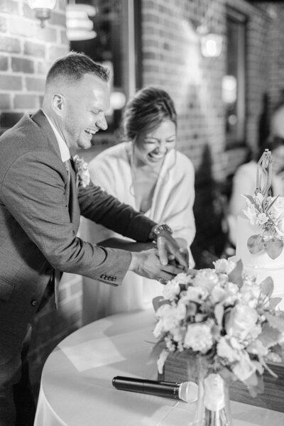 bride and groom smiling and cutting cake