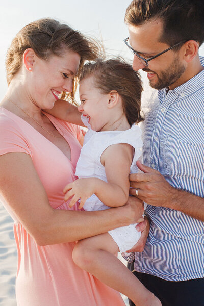 Beach maternity portrait with toddler touching mom's belly