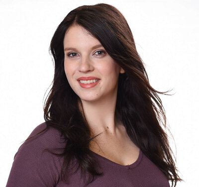 Young female headshot of woman against white backdrop with purple top
