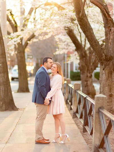 Man kisses his fiancé on the head during their engagement session in downtown New Haven.