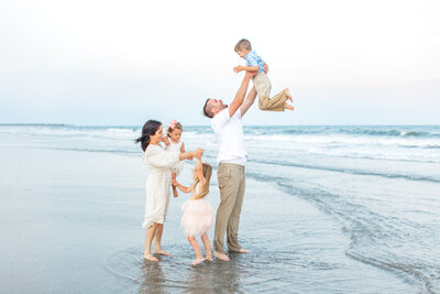 Husband and wife with children in family portrait on the beach in Charleston by Karen Schanely.