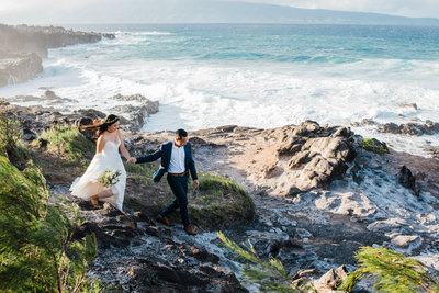 A groom leads his bride to a cliffside location in Maui, Hawaii