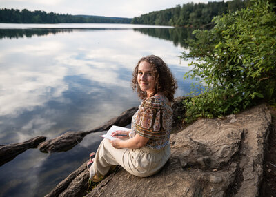 A creative write poses by the lake in Baltimore County, Maryland during her branding session. She is writing while posing.