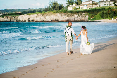 A bride and groom stroll along the sand in Kapalua Maui Hawaii