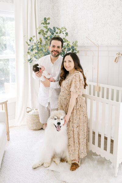 New parents hold newborn baby boy in blue plaid nursery during newborn photography session.