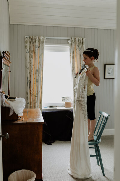 little girl holds up mother's wedding dress