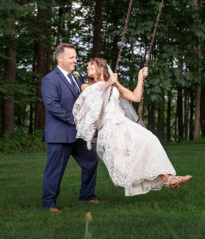 A groom pushing a bride on a swing.