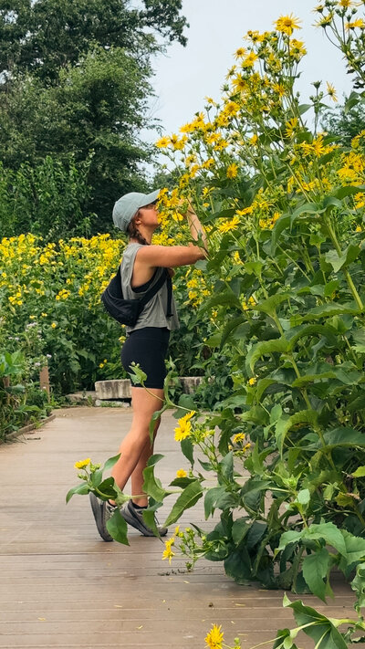 meredith ewenson smelling a spring sunflower on a nature walk in chicago