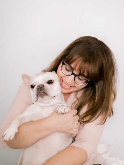 A woman in glasses hugs her dog.