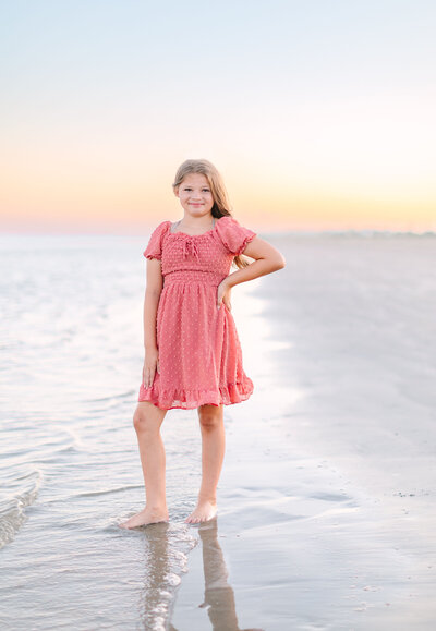 child standing on the beach at sunset