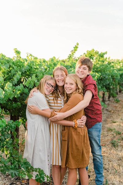 Four teen siblings hugging in a vineyard for their Livermore, CA family photos