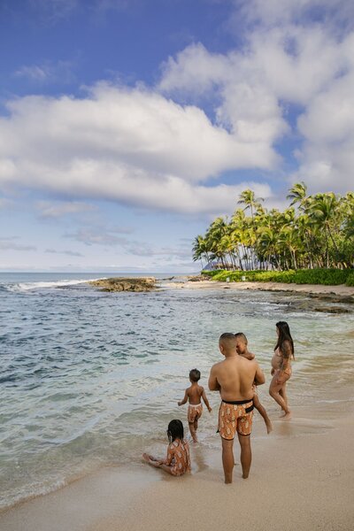 A family of five playing on the beach at Hawaii.