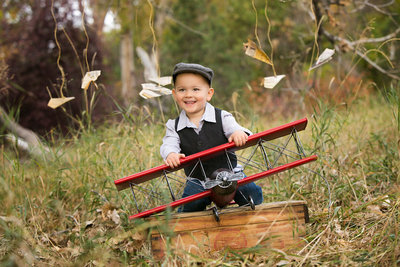 Toddler boy playing with a toy plane during a photo shoot