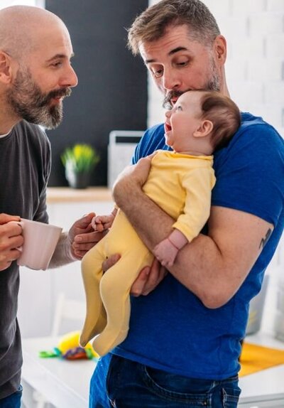 gay couple holding their smiling daughter