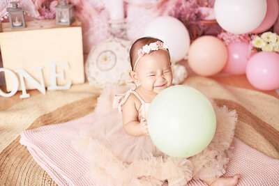 baby girl holding a baloon smiling