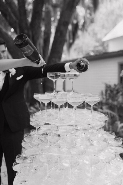 champagne tower with bride and groom at wedding pouring champagne