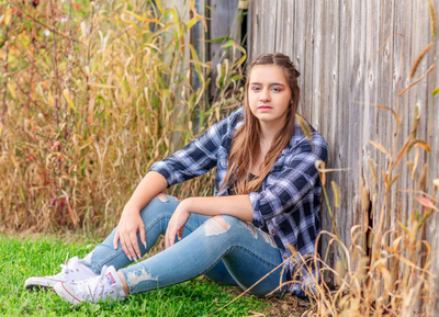 Senior girl sitting in front of a barn