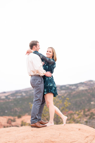 Couple kissing standing on rock for engagement photoshoot at Red Rock Open Space