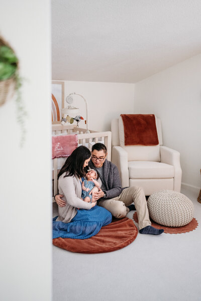 newborn photography session in a families nursery. the mom and dad cuddle their newborn daughter