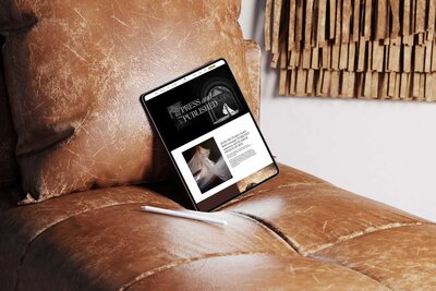 An ipad sits on a brown leather couch with Susan's website