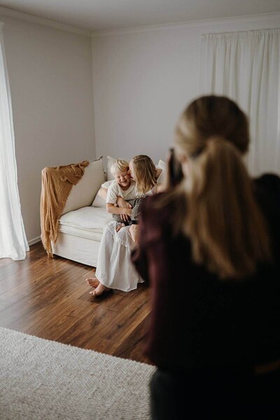Photographer educator aimee kelly takes a photograph of a mother and son while they sit in her studio on the sofa