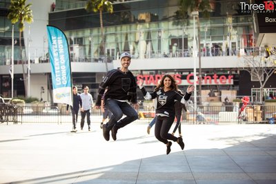 Engaged LA Kings fans jump for joy during their engagement session in front of the Crypto.com Arena