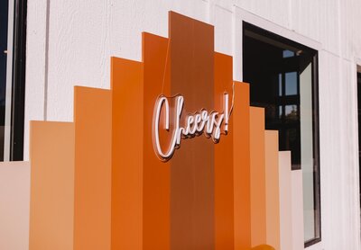colorful orange photo backdrop with neon cheer sign