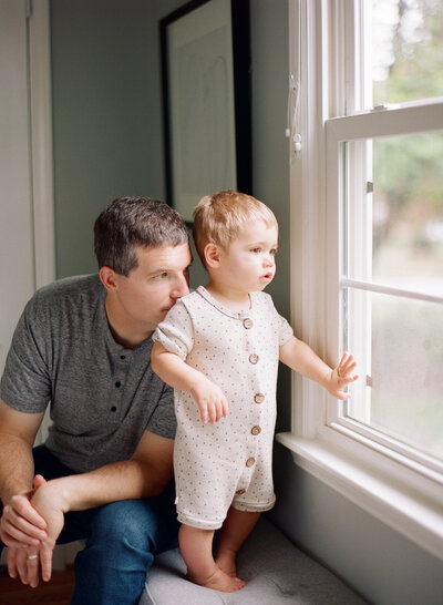 Father and toddler look out the window