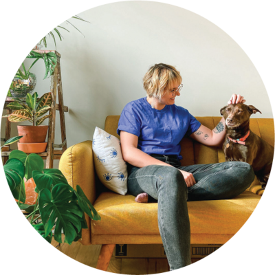 Philadelphia Photographer Heather McBride sitting on a yellow couch petting a dog.