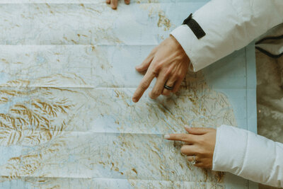 Bride and groom pointing at map of iceland on wedding day.