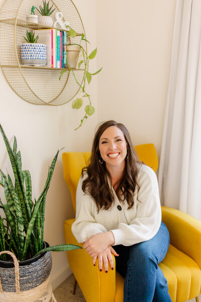 Photographer Mary Catherine sitting on a yellow chair surrounded by plants - DC Family Photographer