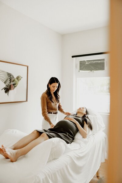 Acupuncturist placing fine needles into a patient’s abdomen during a gentle natural labor induction acupuncture session.