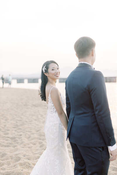 Bride and groom walk alongside Lake Tahoe as bride looks back
