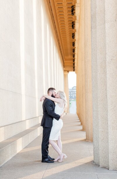 Engaged couple kissing inside the columns at the Nashville Parthenon
