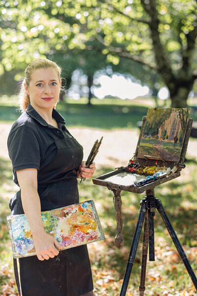 Artist Valérie Pirlot painting outdoors with her easel and brushes in the garden at Chateau Charente during her plein air retreat.
