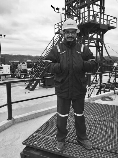 a man in a hard hat stands on an oil rig