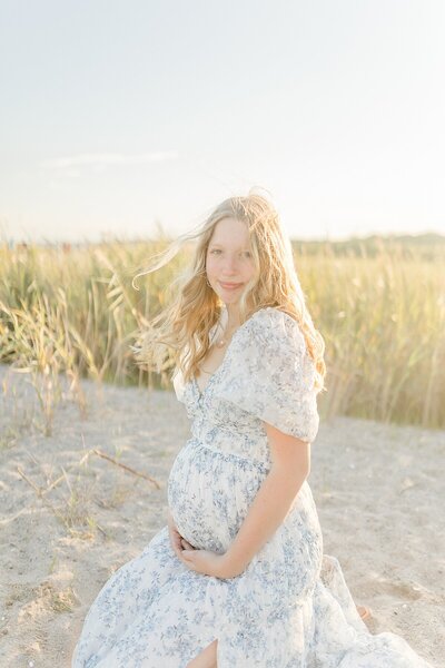 woman in white dress maternity photos at ct beach