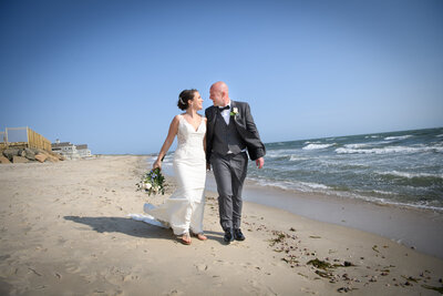 A newlywed couple walking along a beach.