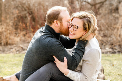Playful Chicago couple laughing and kissing outside during a photo session.