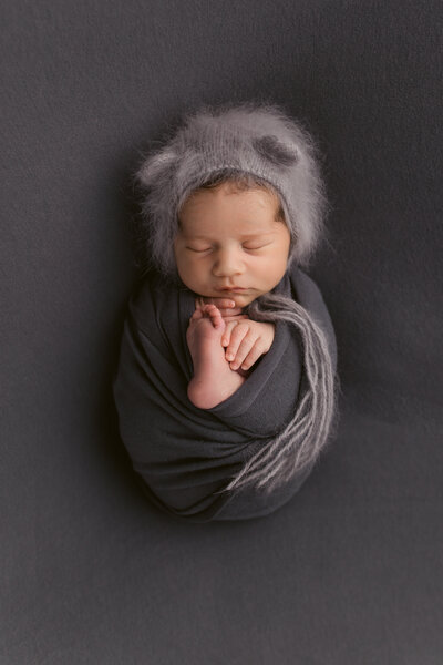 baby boy in black background with fuzzy bonnet on near Hillsboro Oregon