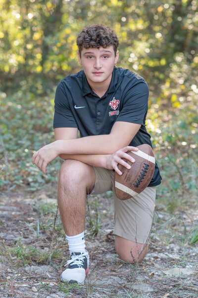 Orlando high school senior photography Khim Higgins photographs a senior boy holding a football.