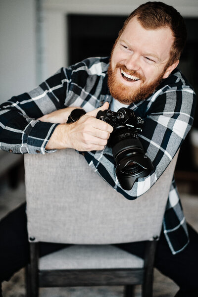 Photographer smiling and laughing while holding a camera
