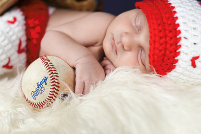 Beautiful Mississippi Newborn Photography: Baby boy wears baseball outfit and holds Rawlings baseball