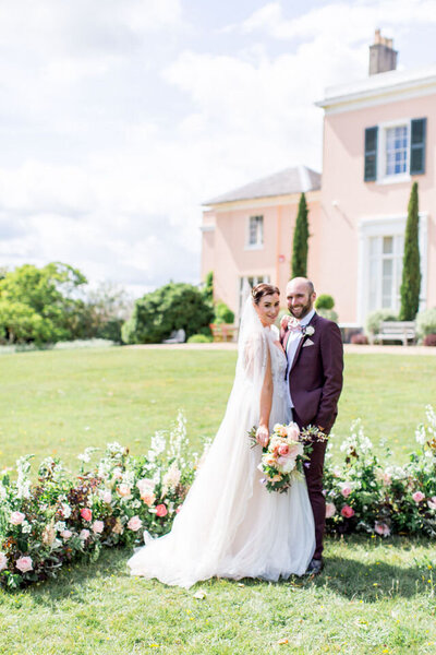 newlywed couple  in garden with flowers in the background
