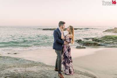 Engaged couple gaze at each other while embracing on Treasure Island Beach in Laguna Beach