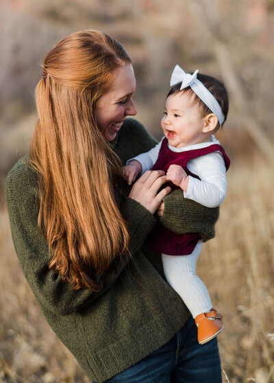 A red-headed mother smiles and laughs with her adorable baby