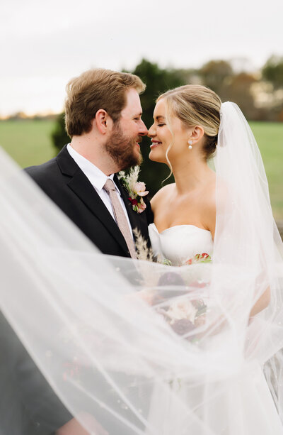 charlottesville virginia wedding with bride and groom leaning into each other until their noses touch while the brides veil flows in the wind