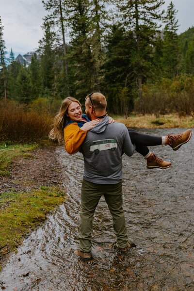 Man holds a woman during a fly fishing engagement shoot.